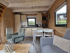 A compact kitchen with wooden cabinets, a dining table, and a seating area with a sofa and chairs.