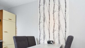 Un comedor con una mesa dispuesta para cuatro, un altavoz en la pared y un armario al fondo.