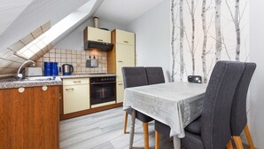 Una cocina compacta con comedor, que incluye un armario de madera, horno integrado y una mesa con sillas.