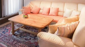 Una sala de estar acogedora con un sofá beige, una mesa de centro de madera y un tapete estampado.