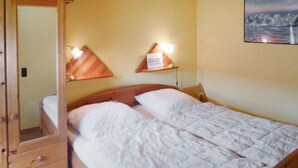 Una cama individual con cabecera de madera, dos mesitas de noche con lámparas y un armario con espejo.