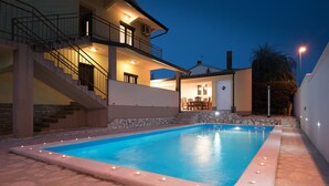 Une piscine rectangulaire bordée de pierres, entourée d’une terrasse également en pierre.