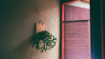 A wall-mounted wooden object with a plant, a textured wall, and a partially visible red-framed window.
