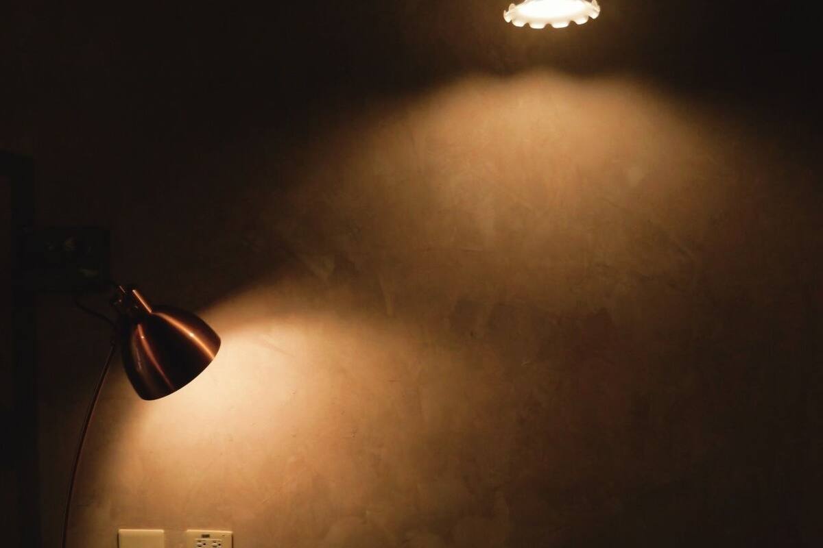 A dimly lit room with a single table lamp and a hanging light fixture.