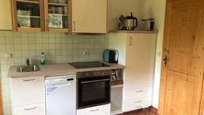Eine kleine Küche mit Geschirrspüler, Backofen und einer Kaffeemaschine auf der Arbeitsfläche.