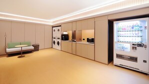 A modern hotel room with a sofa, washing machine, and a vending machine. - Ji Hotel Orchard Singapore (Singapore)