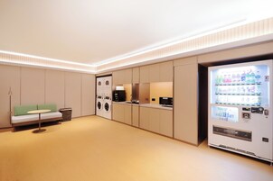 Una habitación de hotel moderna con sofá, lavadora y máquina expendedora.