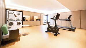 A modern home gym with a treadmill, stationary bike, and washing machines. - Ji Hotel Orchard Singapore (Singapore)