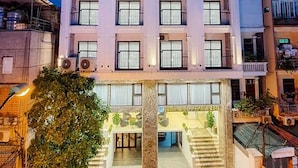 Ett hotell med flera våningar, en central entré, balkonger på varje våningsplan och en skylt som visar att det är ett hotell.