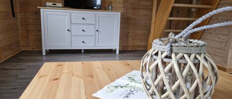 A wooden room with a white cabinet, a flat-screen TV, and a woven basket on a table.