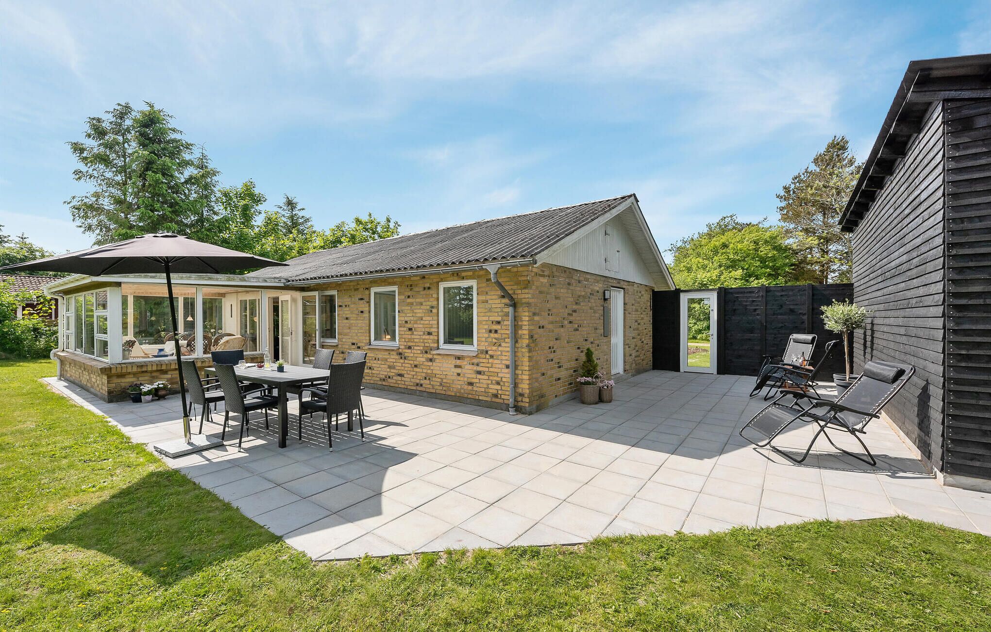 A patio area with a brick building, outdoor furniture, and a covered seating area.