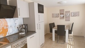 A modern kitchen with a built-in oven, a coffee maker, and a dining area with a table and chairs.