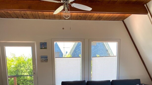 Una sala de estar moderna con un sofá oscuro, una mesa de centro de madera y un ventilador de techo.