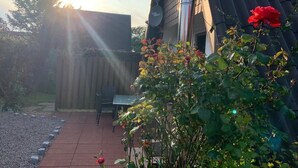 Un patio con mesa y sillas, una cerca de madera y un jardín con rosales.