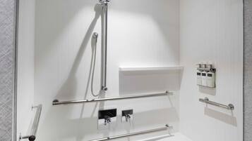 A modern bathroom with a white bathtub, a shower with a handheld showerhead, and a shelf with toiletries.