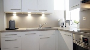 A modern kitchen with white cabinets, a stainless steel sink, and a coffee maker. - Wide view - ideally located family apartment with charm (Wangerooge)