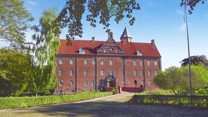 A large red brick building with a central entrance, surrounded by greenery and a cobblestone path. - 6 bedroom stunning home in Grenaa (Grenaa)