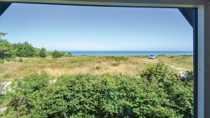 A view through a window of a coastal landscape with a vehicle on a dirt path, dense greenery, and a clear blue sky. - 6 bedroom stunning home in Grenaa (Grenaa)