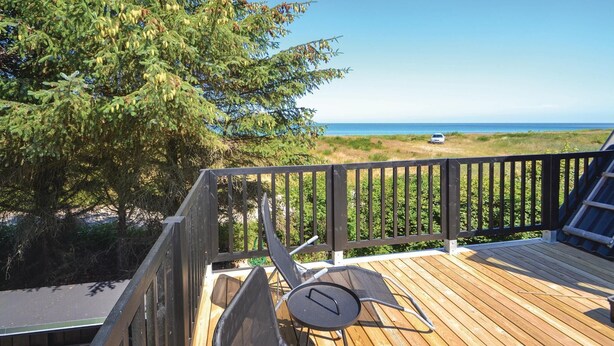 A wooden deck with a view of the ocean and a car parked on the beach. - 6 bedroom stunning home in Grenaa (Grenaa)
