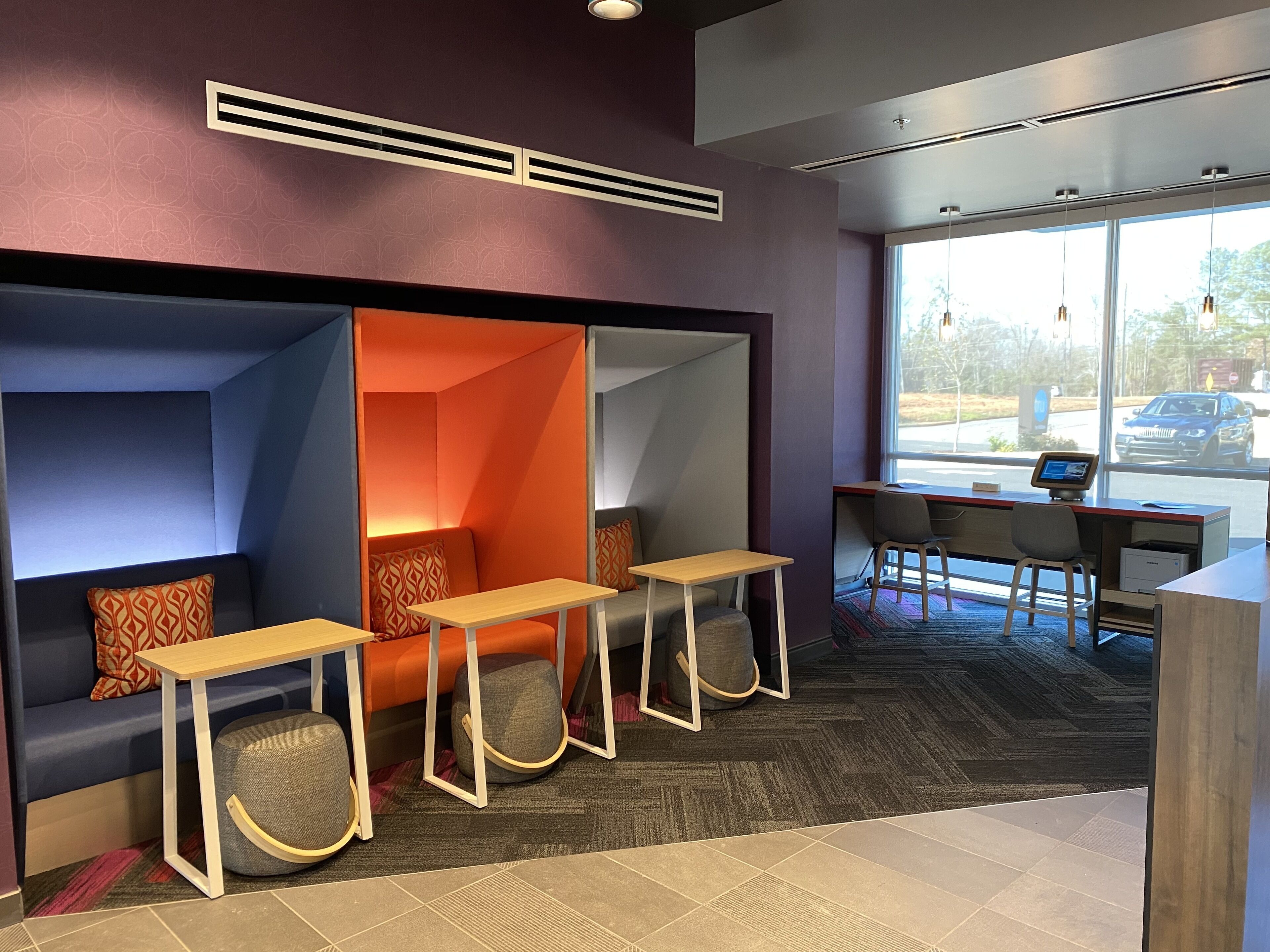 A modern waiting area with seating, a reception desk, and large windows.