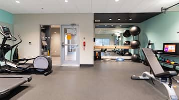 A gym with exercise equipment, a mirror, and a television screen.