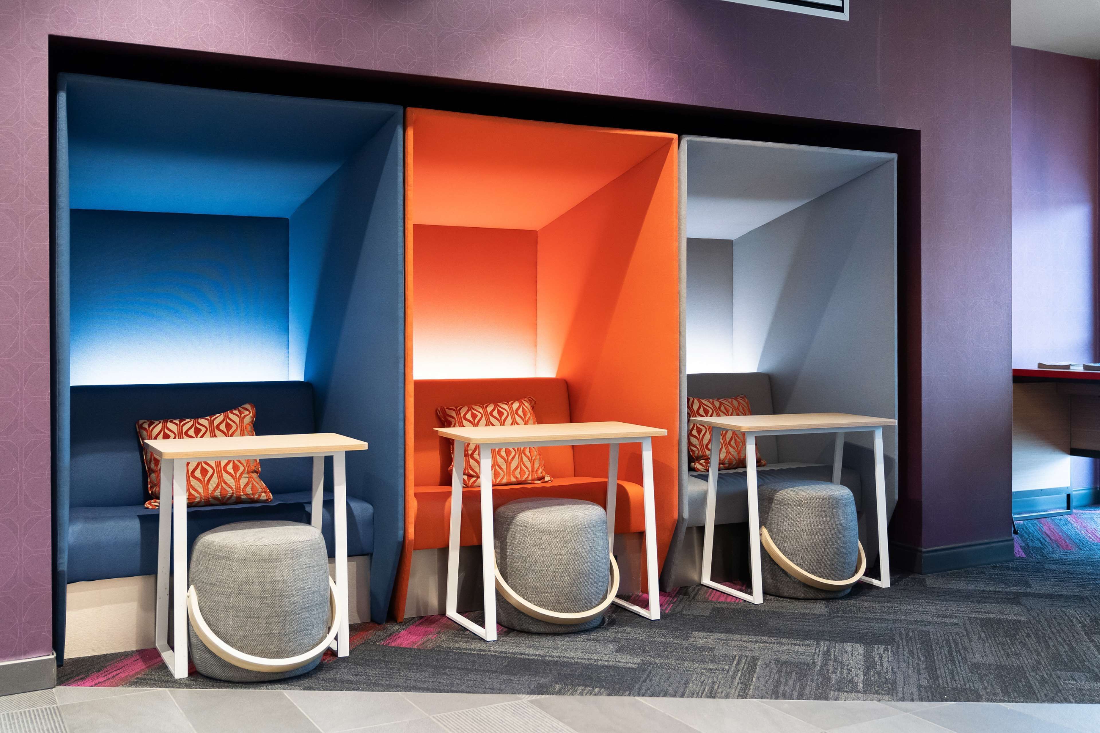 Un espace de bureau moderne comprenant trois coins salon, chacun équipé d’une table et d’un siège rembourré.
