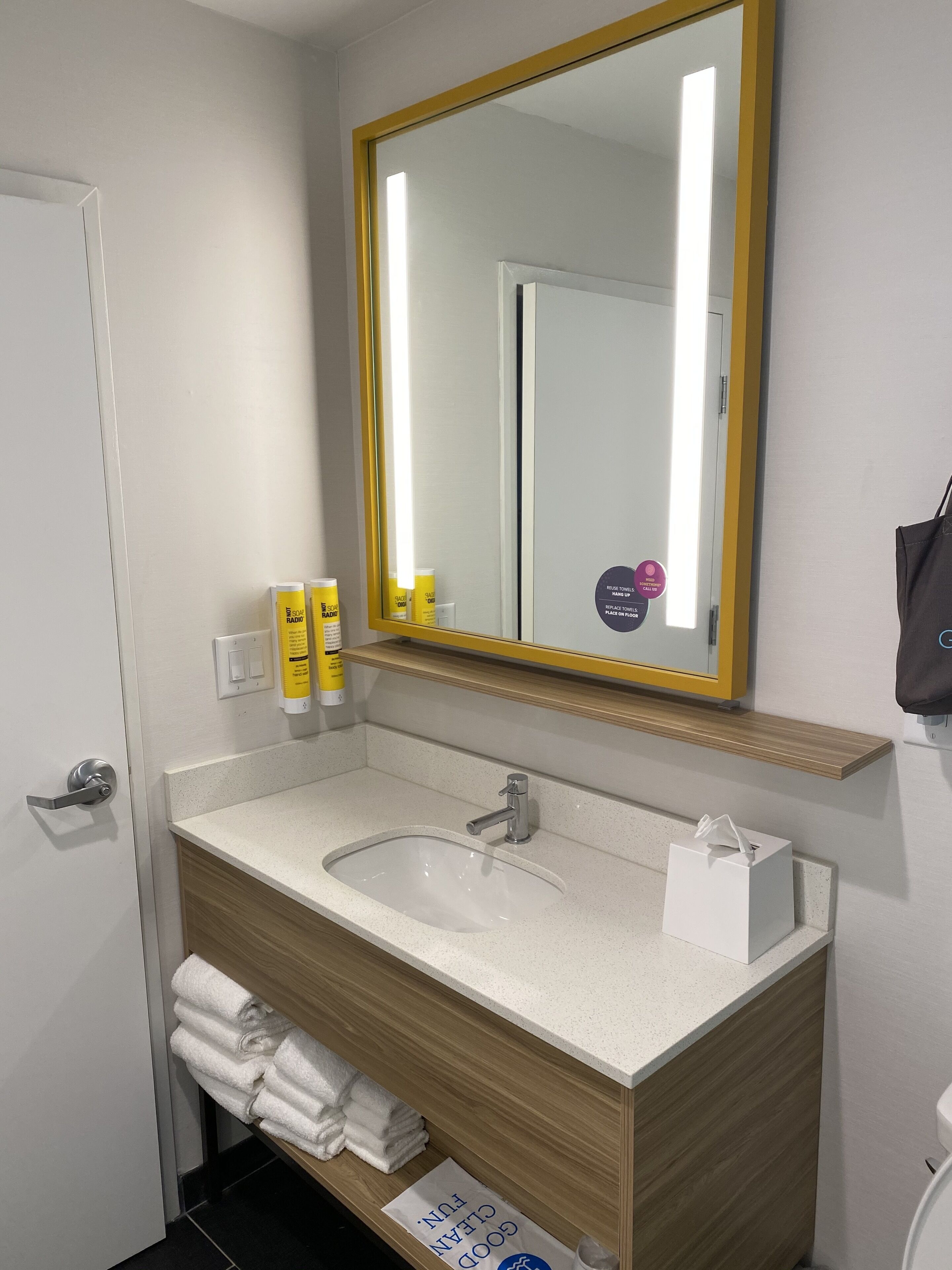 Un baño moderno con un lavabo blanco, un espejo con marco dorado y artículos de aseo en la encimera.