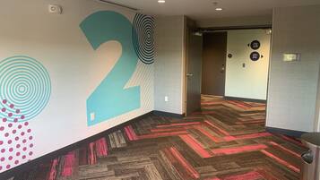 A hallway with a large number '2' on the wall, carpeted with a geometric pattern, and doors labeled with room numbers.