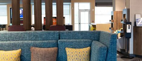 A modern lobby with a blue sectional sofa, wooden columns, and contemporary pendant lighting.