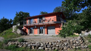 A two-story building with a balcony, a stone staircase, and a garage door.