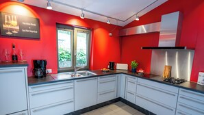A modern kitchen with white cabinets, a stainless steel range hood, and a black countertop.