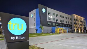 Un hôtel au design moderne, avec une enseigne « tru by Hilton » bien visible à l’entrée.