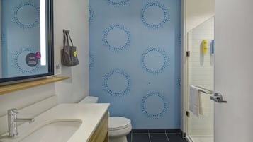 A bathroom with a white sink, toilet, and a shower area with a glass door.