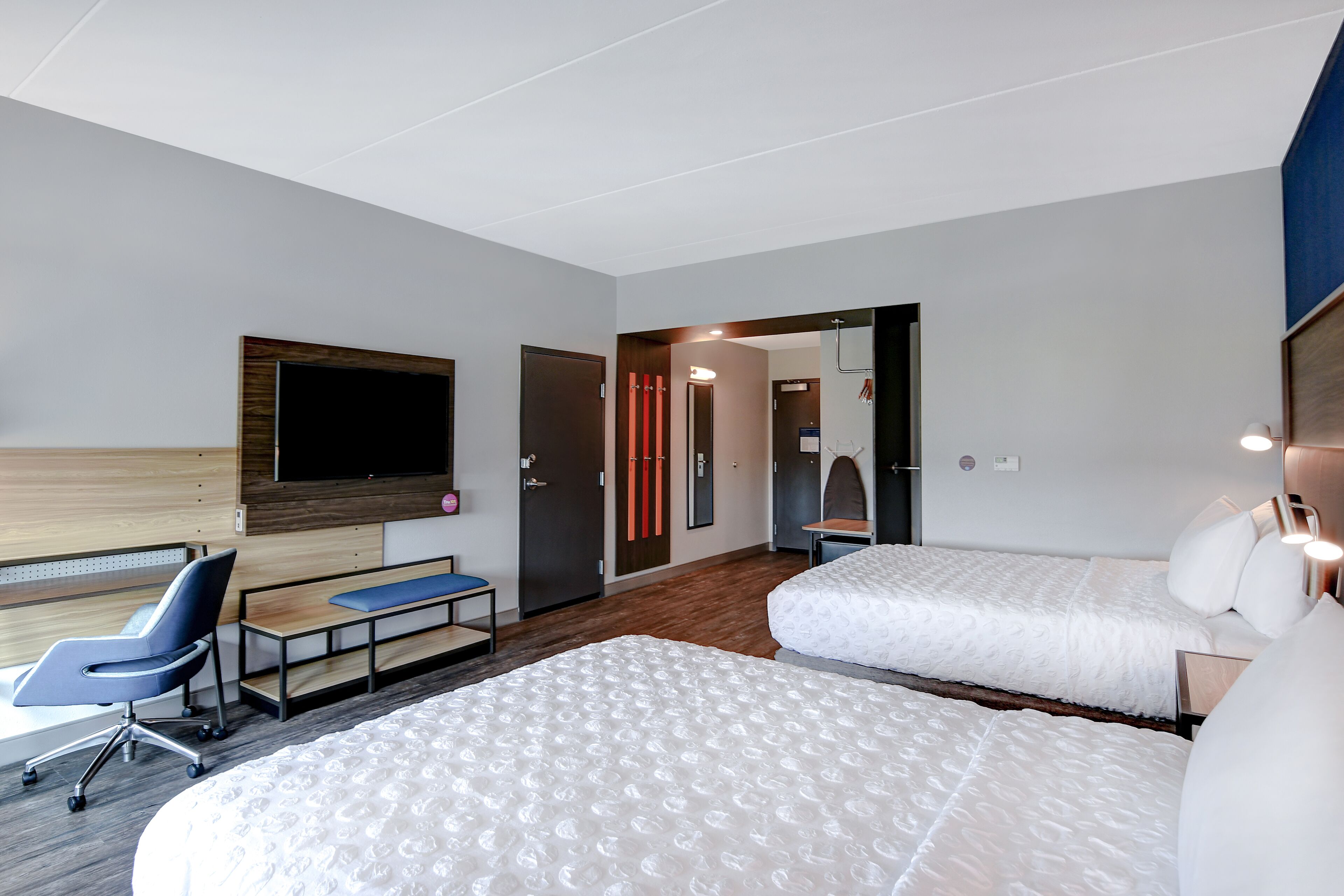 Une chambre d’hôtel avec un lit, un bureau, une chaise, une télévision et une porte.