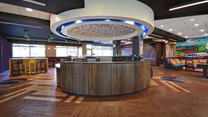 A modern reception area with a central counter, seating, and a mural on the wall. - Tru By Hilton Burlington (Burlington)
