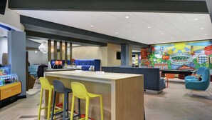 A modern bar area with a wooden counter, colorful bar stools, and a mural depicting Springfield.