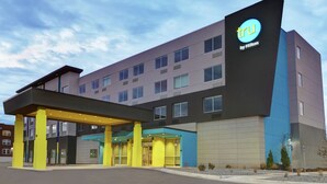 A modern hotel building with a prominent 'tru by Hilton' sign, multiple entry points, and a covered entrance area.