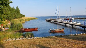 Un rivage paisible où des bateaux sont amarrés à un quai, entouré de berges verdoyantes et d’arbres.