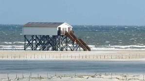 Un muelle de madera que se adentra en el océano, con un pequeño edificio blanco al final.