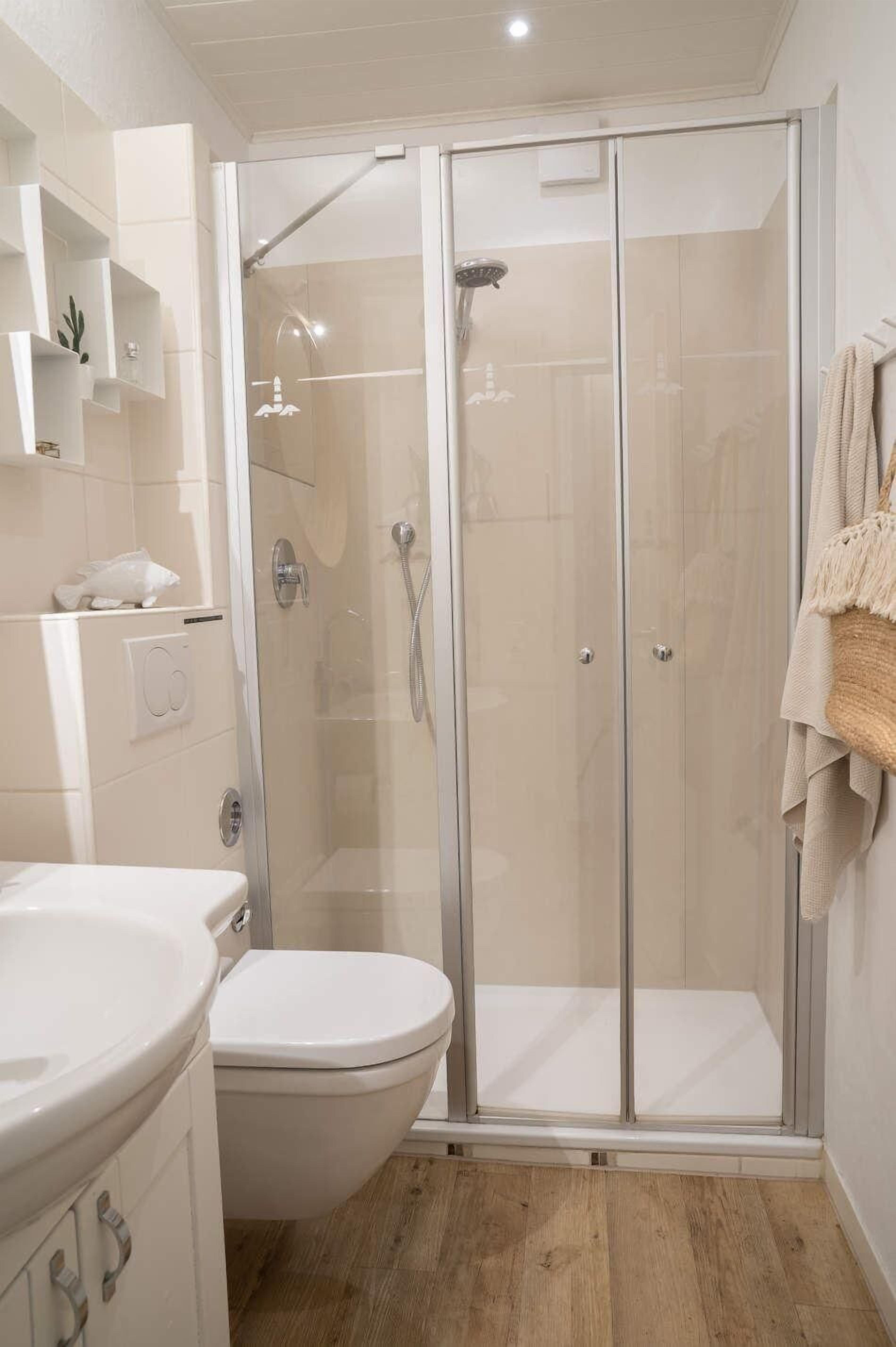 A modern bathroom with a glass-enclosed shower, a toilet, and a sink.