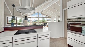 A modern kitchen with white cabinetry, a black stovetop, and a large window offering a view of the outdoors.
