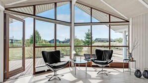 A spacious room with large windows, two black leather chairs, a small round table, and a wooden deck.