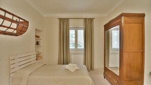 Een slaapkamer met een bed, een houten garderobe, een raam met gordijnen en een radiator.