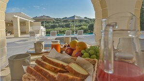 Un coin petit-déjeuner en plein air, avec une table, des chaises et une vue sur un paysage luxuriant.