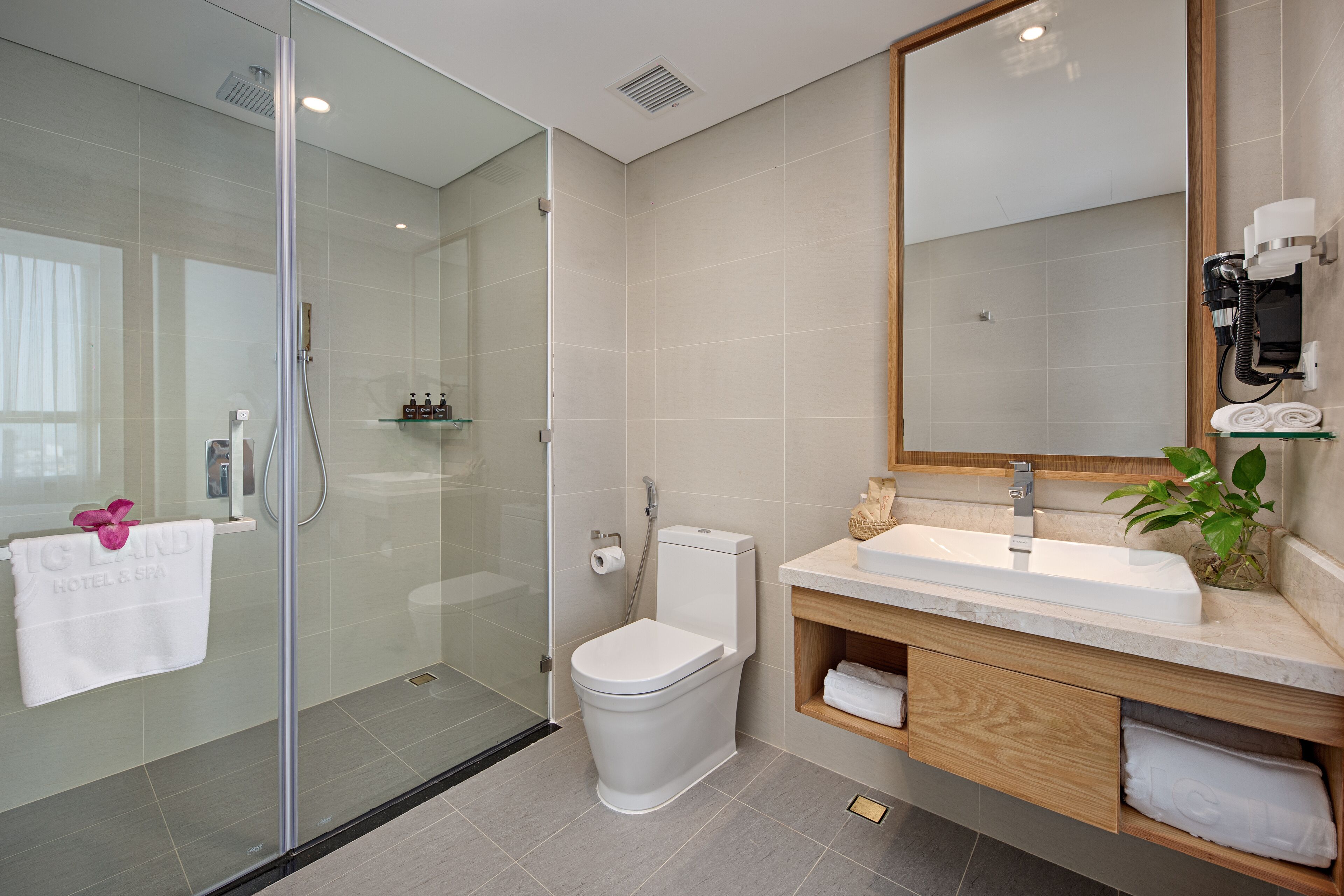 A modern bathroom with a glass-enclosed shower, a white toilet, and a vanity with a sink and mirror.