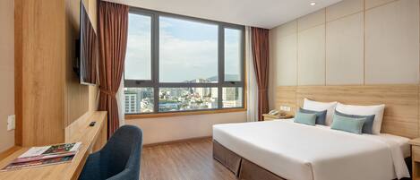 A hotel room with a large bed, a desk, and a TV.
