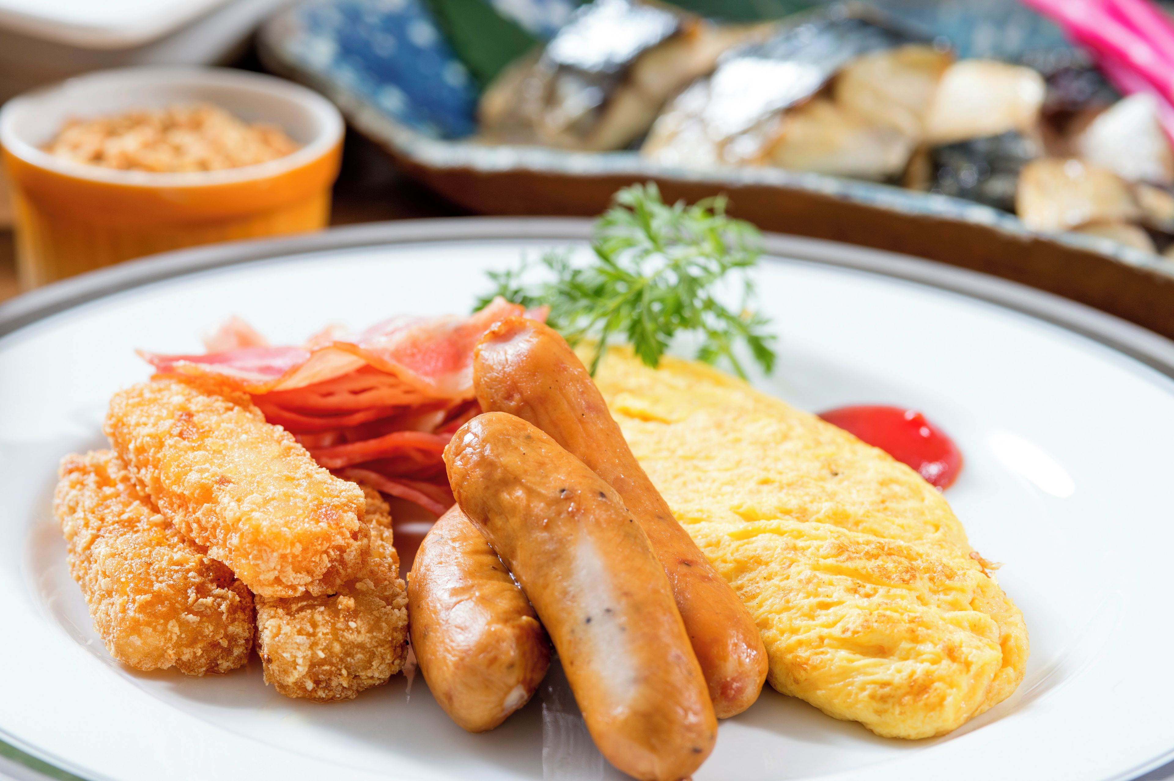 Une assiette contenant du poulet pané, des saucisses et une omelette.