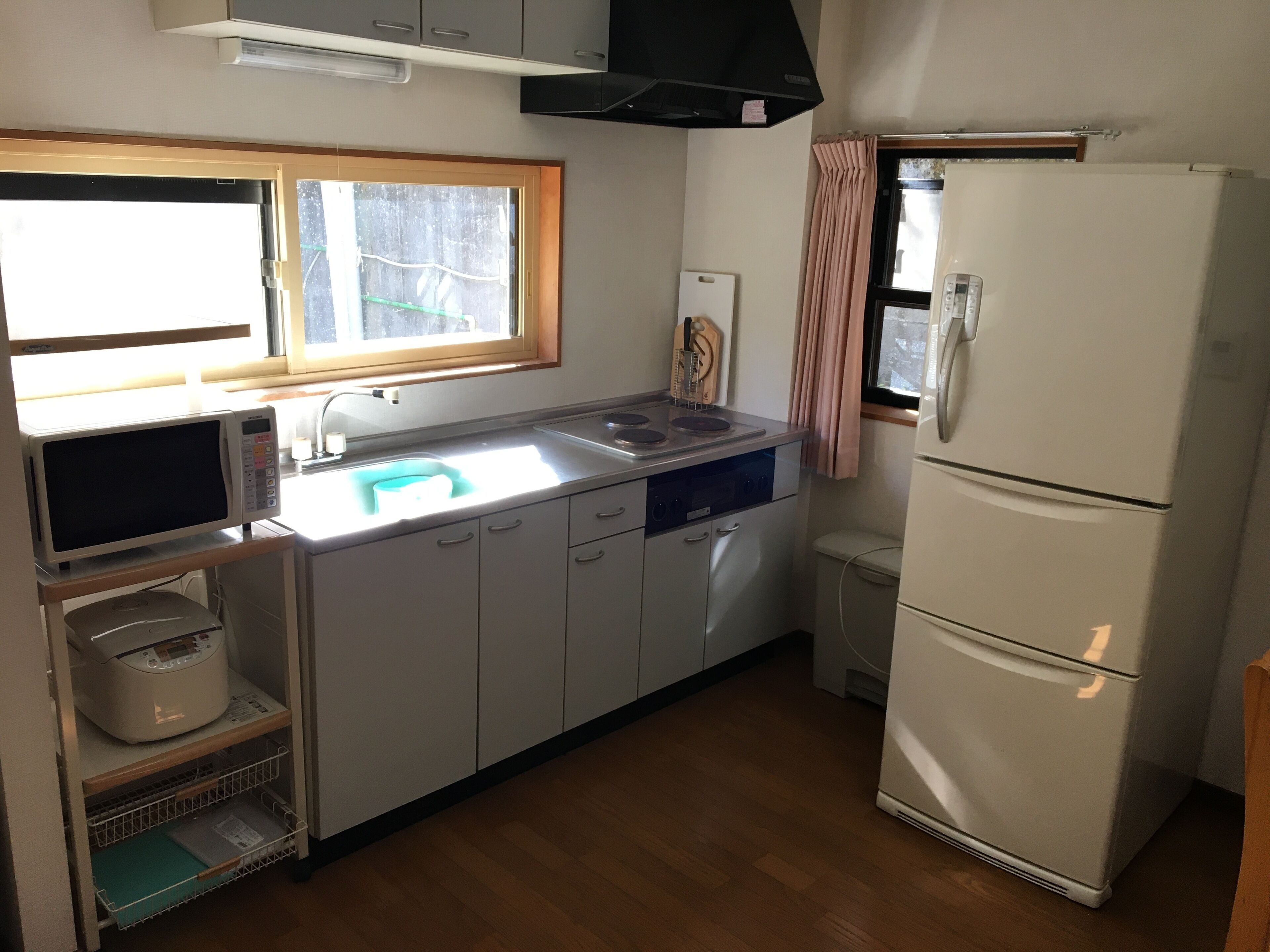 A compact kitchen with a microwave, sink, stove, and refrigerator.