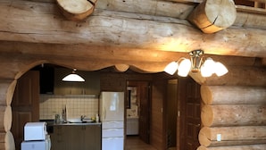 A log cabin interior with a kitchen, dining area, and wooden walls. - Hakuba Canadian Lodge (Hakuba)