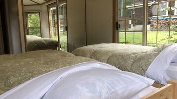 A room with two beds, a large window, and a view of a garden.